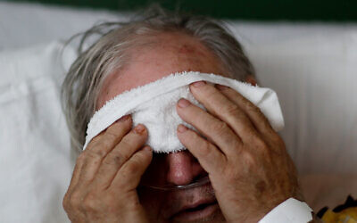 Photo d'lllustration : Un patient atteint par la grippe qui place une compresse froide sur son visage. (Crédit : AP Photo/David Goldman)