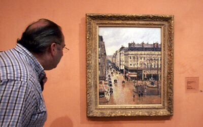 Cette photo d'archive du 12 mai 2005 montre un visiteur regardant le tableau impressionniste intitulé "Rue St.-Honoré, Apres-Midi, Effet de Pluie" peint en 1897 par Camille Pissarro, exposé au Musée Thyssen-Bornemisza de Madrid. (Crédit : AP Photo/Mariana Eliano, Archive)