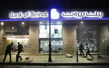 Des manifestants anti-gouvernementaux brisent une veuve de banque lors de manifestations contre le gouverneur de la banque centrale libanaise et contre l'aggravation de la crise financière, le 14 janvier 2020, à Beyrouth, au Liban. (Crédit : AP/Hussein Malla)