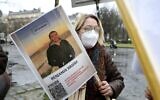 Une femme tient une photo de Benjamin Brière lors d'un rassemblement à Paris, en France, le samedi 8 janvier 2022. Le touriste français emprisonné en Iran depuis l'année dernière a entamé une grève de la faim pour protester contre les mauvais traitements en prison, selon sa sœur et son avocat. Brière, 36 ans, a été arrêté en mai 2020 après avoir pris des photos dans une zone désertique où la photographie est interdite. (Crédit : AP Photo/Adrienne Surprenant)