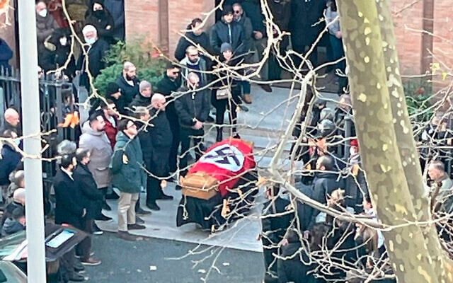 Une photo mise à disposition par le portail d'information en ligne italien Open, montrant des personnes rassemblées autour d'un cercueil recouvert d'une croix gammée devant l'église Sainte-Lucie, à Rome, le lundi 10 janvier 2022. (Crédit : Open Via AP) Une photo mise à disposition par le portail d'information en ligne italien Open, montrant des personnes rassemblées autour d'un cercueil recouvert d'une croix gammée devant l'église Sainte-Lucie, à Rome, le lundi 10 janvier 2022. (Crédit : Open Via AP)