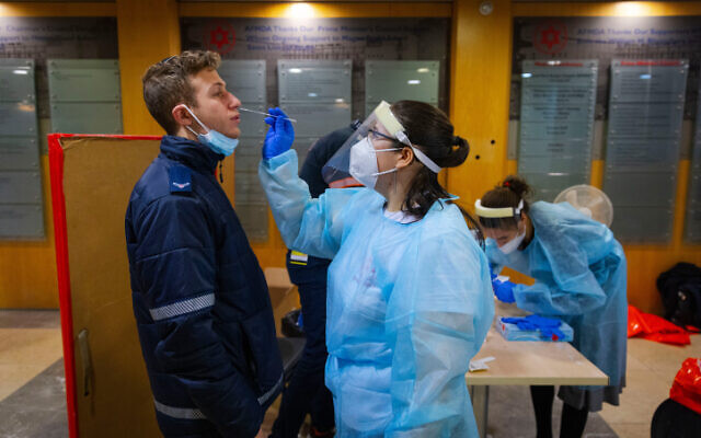 Une infirmière du Magen David Adom effectue un test antigénique sur l'un de ses collègues dans un centre de dépistage de Jérusalem, le 9 janvier 2022. (Crédit : Olivier Fitoussi/Flash90) Une infirmière du Magen David Adom effectue un test antigénique sur l'un de ses collègues dans un centre de dépistage de Jérusalem, le 9 janvier 2022. (Crédit : Olivier Fitoussi/Flash90)