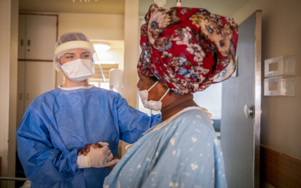 Un soignant et une patiente dans l'unité COVID de l'hôpital Kaplan à Rehovot, le 18 janvier 2022. (Crédit : Yossi Aloni/Flash90) Un soignant et une patiente dans l'unité COVID de l'hôpital Kaplan à Rehovot, le 18 janvier 2022. (Crédit : Yossi Aloni/Flash90)