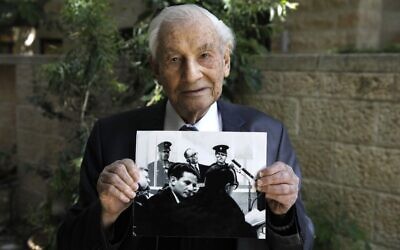 Gabriel Bach, ancien juge à la Cour suprême et ancien procureur-adjoint pendant le procès d'Adolf Eichmann, pose avec une photo le montrant (dessous) avec Eichmann (au-dessus) le 3 mai 2020. (Crédit : MENAHEM KAHANA/AFP)