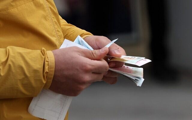 Un homme compte des billets en quittant un bureau de change à Ankara, en Turquie, le 23 février 2022. (Crédit : Adem ALTAN / AFP) Un homme compte des billets en quittant un bureau de change à Ankara, en Turquie, le 23 février 2022. (Crédit : Adem ALTAN / AFP)