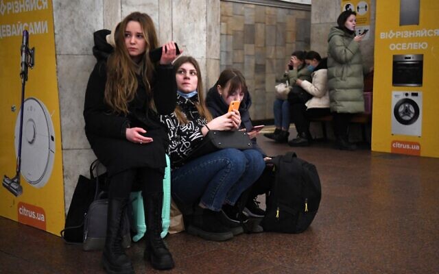 Des jeunes filles tiennent leur téléphone portable alors qu'elles se réfugient dans une station de métro à Kiev, dans la matinée du 24 février 2022. (Crédit : Daniel LEAL / AFP) Des jeunes filles tiennent leur téléphone portable alors qu'elles se réfugient dans une station de métro à Kiev, dans la matinée du 24 février 2022. (Crédit : Daniel LEAL / AFP)