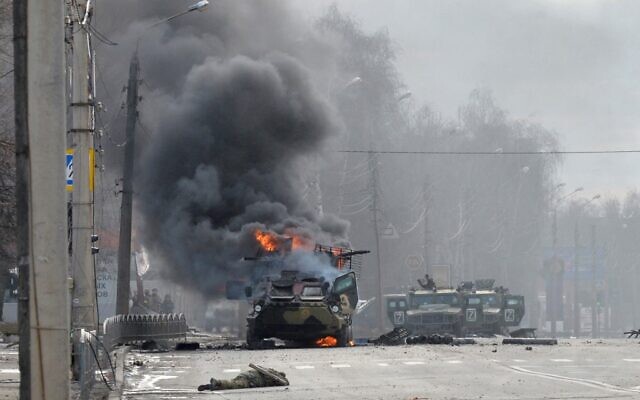 Cette photo prise le 27 février 2022 montre un véhicule blindé de transport de troupes russe brûlant à côté du corps d'un soldat non identifié lors d'un combat avec les forces armées ukrainiennes à Kharkiv. Les forces ukrainiennes ont gardé le contrôle total de Kharkiv le 27 février 2022 à la suite de combats de rue avec les troupes russes dans la deuxième plus grande ville du pays, a déclaré le gouverneur local. (Crédit : Sergueï BOBOK / AFP) Cette photo prise le 27 février 2022 montre un véhicule blindé de transport de troupes russe brûlant à côté du corps d'un soldat non identifié lors d'un combat avec les forces armées ukrainiennes à Kharkiv. Les forces ukrainiennes ont gardé le contrôle total de Kharkiv le 27 février 2022 à la suite de combats de rue avec les troupes russes dans la deuxième plus grande ville du pays, a déclaré le gouverneur local. (Crédit : Sergueï BOBOK / AFP)