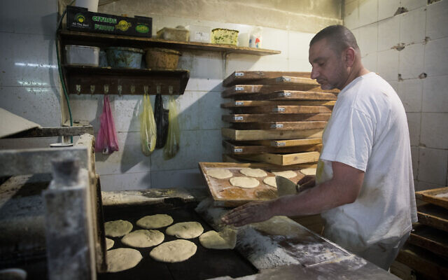 Un homme préparant une pita dans une boulangerie du marché de Mahane Yehuda à Jérusalem, le 16 avril 2020 (Credit: Yonatan Sindel/Flash90) Un homme préparant une pita dans une boulangerie du marché de Mahane Yehuda à Jérusalem, le 16 avril 2020 (Credit: Yonatan Sindel/Flash90)