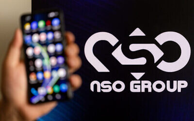 Une personne tient un téléphone avec le logo de NSO en arrière-plan, à Jérusalem, le 7 février 2022. (Crédit : Yonatan Sindel/Flash90)
