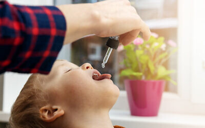 Une mère donne à son enfant des gouttes de vitamine D. (Crédit : iStock via Getty Images)