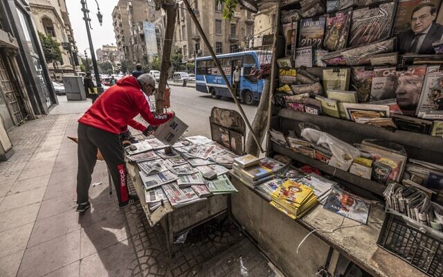 Un vendeur range des journaux dans un kiosque à journaux le long de la rue Kasr al-Aini, dans le centre de la capitale égyptienne, Le Caire, le 17 février 2022. (Crédit : Khaled DESOUKI / AFP) Un vendeur range des journaux dans un kiosque à journaux le long de la rue Kasr al-Aini, dans le centre de la capitale égyptienne, Le Caire, le 17 février 2022. (Crédit : Khaled DESOUKI / AFP)