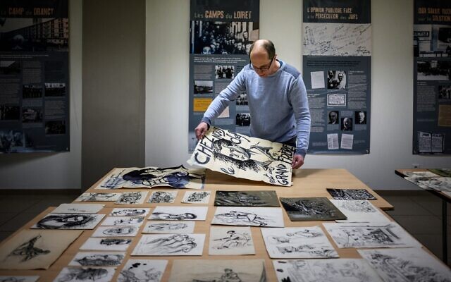 Directeur français du Musée de la Résistance et de la Déportation en Ardèche, Rémi Fourche examine des dessins et des affiches envoyés par un donateur anonyme à Le Teil, dans le sud de la France, le 1er mars 2022. (Crédit : JEFF PACHOUD / AFP)