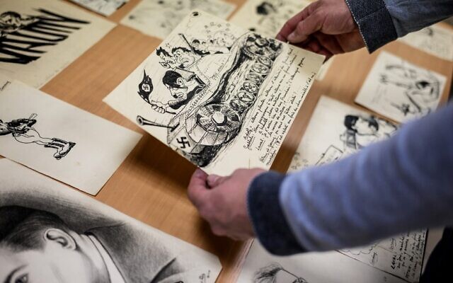Directeur français du Musée de la Résistance et de la Déportation en Ardèche, Rémi Fourche examine des dessins et des affiches envoyés par un donateur anonyme à Le Teil, dans le sud de la France, le 1er mars 2022. (Crédit : JEFF PACHOUD / AFP)