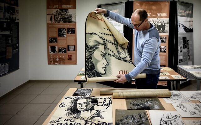 Directeur français du Musée de la Résistance et de la Déportation en Ardèche, Rémi Fourche examine des dessins et des affiches envoyés par un donateur anonyme à Le Teil, dans le sud de la France, le 1er mars 2022. (Crédit : JEFF PACHOUD / AFP)