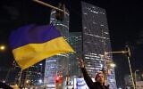Une femme brandit un drapeau ukrainien lors d’une manifestation contre l’invasion militaire de l’Ukraine par la Russie, à Tel-Aviv, sur la côte méditerranéenne d’Israël, le 12 mars 2022. (JACK GUEZ / AFP)