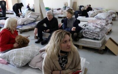 Des réfugiés juifs ukrainiens qui ont fui la guerre dans leur pays attendent dans un hangar de la capitale moldave Chisinau le 15 mars 2022, avant de se rendre à l'aéroport pour embarquer dans un avion pour Israël. (Crédit : Gil Cohen-Magen / AFP)
