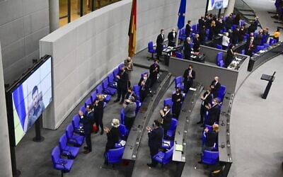Le président ukrainien Volodymyr Zelensky à l'écran, reçoit une standing ovation des membres du gouvernement et du parlement après s'être adressé par liaison vidéo à la chambre basse du parlement allemand Bundestag, à Berlin, le 17 mars 2022 . (Crédit : Tobias SCHWARZ/AFP)