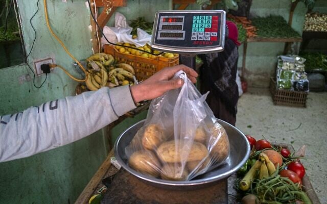 Un Egyptien pèse des pommes de terre sur un marché du Caire, le 17 mars 2022. (Crédit : Khaled DESOUKI / AFP)