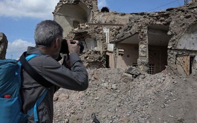 Un touriste prend des photos de la destruction causée par des années de conflit dans la ville de Mossoul, dans le nord de l'Irak, le 12 mars 2022. (Crédit : Zaid AL-OBEIDI / AFP) Un touriste prend des photos de la destruction causée par des années de conflit dans la ville de Mossoul, dans le nord de l'Irak, le 12 mars 2022. (Crédit : Zaid AL-OBEIDI / AFP)