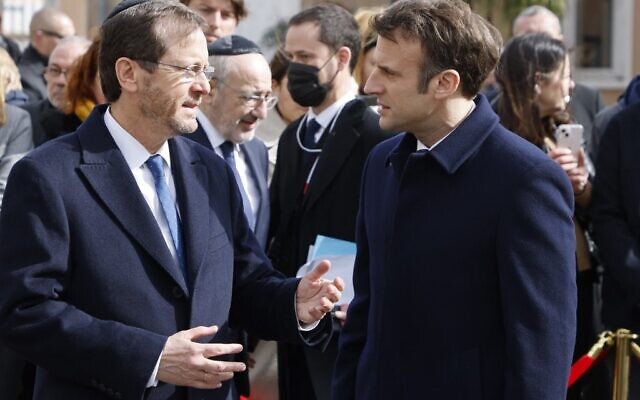 Le président français Emmanuel Macron  écoute le président israélien Isaac Herzog alors qu'ils assistent au collège et au lycée Ohr Torah à Toulouse, dans le sud de la France, le 20 mars 2022, à une cérémonie de commémoration du dixième anniversaire des attentats perpétrés par Mohamed Merah qui ont tué sept personnes en 2012. (Crédit : Ludovic MARIN / POOL / AFP)