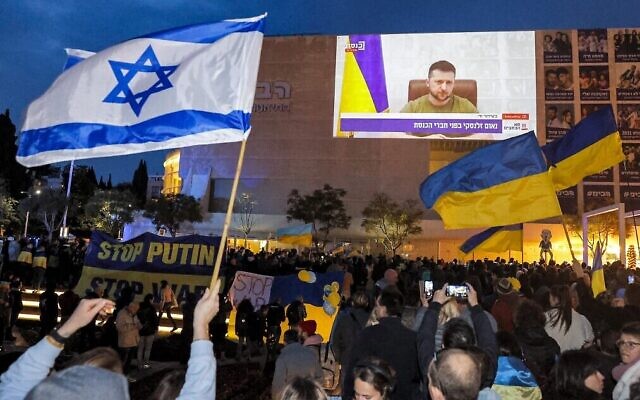 Des manifestants sur la place Habima de Tel Aviv regardent le discours en visioconférence prononcé par le président ukrainien Volodymyr Zelensky, le 20 mars 2022. (Crédit : Jack Guez/ AFP)