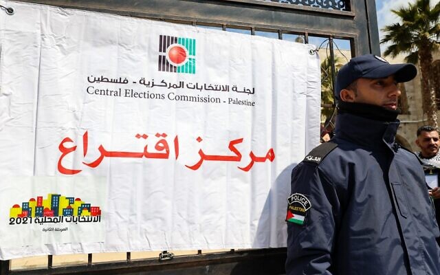 Un policier palestinien monte la garde aux bords d'un bureau de vote lors des élections locales dans la ville de Hébron en Cisjordanie, le 26 mars 2022. (Crédit : Hazem Bader/AFP) Un policier palestinien monte la garde aux bords d'un bureau de vote lors des élections locales dans la ville de Hébron en Cisjordanie, le 26 mars 2022. (Crédit : Hazem Bader/AFP)
