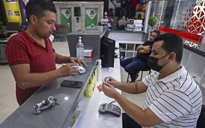 Un Palestinien perçoit une aide financière dans un supermarché de la ville de Gaza, le 15 septembre 2021, dans le cadre du programme d’aide humanitaire en espèces de l’ONU, soutenu par l’État du Qatar. (Crédit : Mahmud Hams/AFP)