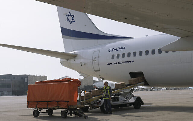 Des ouvriers chargeant des paquets de l'aide humanitaire israélienne pour venir en aide aux personnes prises dans les combats en Ukraine, à l'aéroport Ben Gurion, le 1er mars 2022 (Crédit : Tsafrir Abayov /AP Photo).