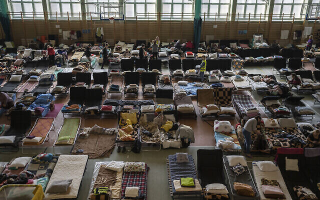 Des réfugiés de guerre ukrainiens se reposant dans un gymnase converti en centre d'accueil, dans le village de Medyka, un poste frontalier entre la Pologne et l’Ukraine, le 15 mars 2022. (Crédit : AP Photo/Petros Giannakouris/Dossier) Des réfugiés de guerre ukrainiens se reposant dans un gymnase converti en centre d'accueil, dans le village de Medyka, un poste frontalier entre la Pologne et l’Ukraine, le 15 mars 2022. (Crédit : AP Photo/Petros Giannakouris/Dossier)