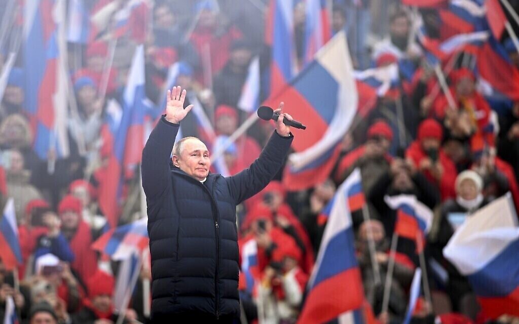 Le président russe Vladimir Poutine salue la foule après son discours au concert marquant le 8e anniversaire du référendum sur le statut de la Crimée et de Sébastopol et sur sa réunification avec la Russie à Moscou, le 18 mars 2022. (Crédit : Ramil Sitdikov/Sputnik Pool Photo via AP)