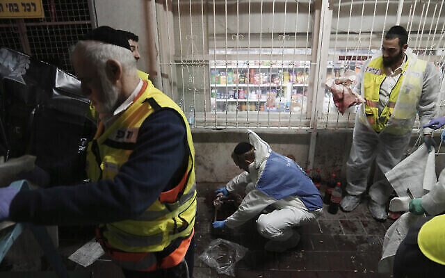 Des bénévoles de la Zaka nettoient le sang dans une rue où un homme armé a ouvert le feu, tuant cinq personnes au total, à Bnei Brak, le 29 mars 2022. (Crédit : AP Photo/Oded Balilty) Des bénévoles de la Zaka nettoient le sang dans une rue où un homme armé a ouvert le feu, tuant cinq personnes au total, à Bnei Brak, le 29 mars 2022. (Crédit : AP Photo/Oded Balilty)