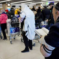 Des Juifs ukrainiens qui ont fui l'invasion russe priant à l'aéroport international de Chisinau, alors qu'ils se dirigent vers Israël, en Moldavie, le 6 mars 2022. (Crédit : Nati Shohat/Flash90)