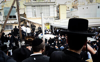 Des gens se rassemblent devant la maison du rabbin Chaim Kanievsky, dans la ville de Bnei Brak, en Israel, le 18 mars 2022. (Crédit : Flash90)