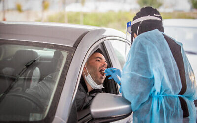 Un infirmier prélève un échantillon dans un centre de dépistage du coronavirus de type drive-in à Modiin, le 21 mars 2022. (Crédit : Yossi Aloni/Flash90)