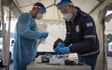 Un collaborateur du service de secours du Magen David Adom effectue un test antigénique rapide de la COVID-19, dans un centre de dépistage automobile du Magen David Adom installé à Jérusalem, le 22 mars 2022. (Crédit : Olivier Fitoussi/Flash90)