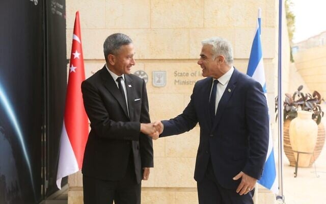 Le ministre des Affaires étrangères Yair Lapid, à droite, serre la main au ministre des Affaires étrangères de Singapour,  Vivian Balakrishnan, aux abords du ministère des Affaires étrangères de Jérusalem, le 21 mars 2022. (Crédit :  Miri Shimonovich/GPO)