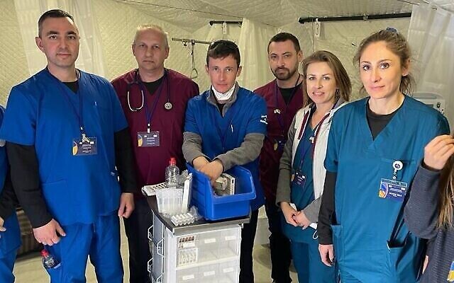 Personnel médical, représentants des gouvernements ukrainien et israélien et patients sont photographiés à l’hôpital de campagne israélien de Mostyska, en Ukraine, qui a ouvert ses portes le 22 mars 2022. (Crédit : Carrie Keller-Lynn/The Times of Israel)