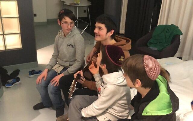 Un moniteur du Habad Camp Yeka joue de la guitare avec ses campeurs, des orphelins juifs d'Odessa, après leur fuite d'Ukraine vers Berlin, mars 2022 (Crédit : avec la permission du Camp Yeka)