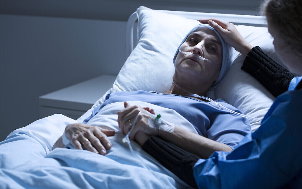 Un bénévole au chevet d'une femme mourant d'une tumeur dans une chambre d'hôpital. (Crédit : iStock) Un bénévole au chevet d'une femme mourant d'une tumeur dans une chambre d'hôpital. (Crédit : iStock)