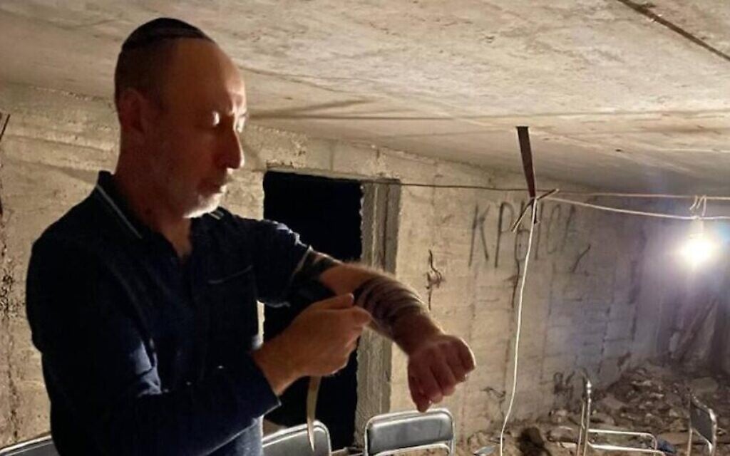 Un homme juif met des tefillin, des phylactères de prière, avant de prier dans un abri anti-aérien à Marioupol, en Ukraine, au cours de la première semaine de la guerre de la Russie contre l'Ukraine. (Crédit : JTA) Un homme juif met des tefillin, des phylactères de prière, avant de prier dans un abri anti-aérien à Marioupol, en Ukraine, au cours de la première semaine de la guerre de la Russie contre l'Ukraine. (Crédit : JTA)