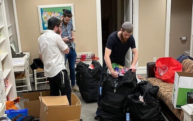Avraham Branover, Sholom Freidfertig et Moishe Lifshitz préparent des valises de fournitures et de jeux pour leurs campeurs du Habad Camp Yeka, qui ont fui l'Ukraine vers Vienne, en mars 2022 (Crédit : avec la permission du Camp Yeka)