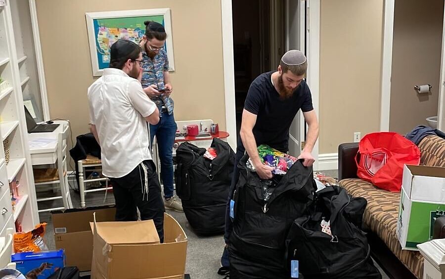 Avraham Branover, Sholom Freidfertig et Moishe Lifshitz préparent des valises de fournitures et de jeux pour leurs campeurs du Habad Camp Yeka, qui ont fui l'Ukraine vers Vienne, en mars 2022 (Crédit : avec la permission du Camp Yeka)