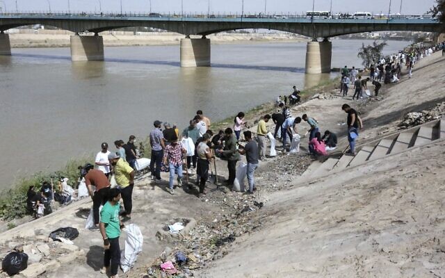 De jeunes volontaires irakiens participent à une campagne de nettoyage sur la rive du fleuve Tigre dans le district d'Adhamiyah de la capitale Bagdad, le 11 mars 2022. (Crédit : Sabah ARAR / AFP) De jeunes volontaires irakiens participent à une campagne de nettoyage sur la rive du fleuve Tigre dans le district d'Adhamiyah de la capitale Bagdad, le 11 mars 2022. (Crédit : Sabah ARAR / AFP)