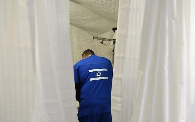 Un membre du personnel médical traite un patient à l’hôpital de campagne israélien, à Mostyska près de la frontière polonaise, à Lviv, dans l’ouest de l’Ukraine, le 23 mars 2022. (Crédit : Yuriy Dyachyshyn/AFP)
