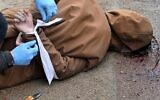 Un employé municipal libère les poignets d'un homme mort, les mains attachées derrière le dos, dans la ville de Boutcha, non loin de la capitale ukrainienne Kiev, le 3 avril 2022. (Crédit :  Sergei SUPINSKY / AFP)