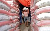 Des travailleurs yéménites portent des sacs de farines dans une boulangerie de la capitale Sanaa, au Yemen, le 27 mars 2022. (Crédit : MOHAMMED HUWAIS / AFP)