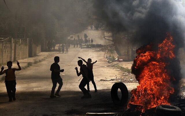 Des enfants palestiniens brûlent des pneus suite à un raid à Jénine, en Cisjordanie, le 12 avril 2022. (Crédit : JAAFAR ASHTIYEH / AFP)