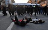 Un homme étendu dans la rue alors que les forces anti-émeute avancent pour disperser les étudiants qui manifestent devant l'Université de la Sorbonne, à Paris, le 14 avril 2022, dix jours avant le second tour de l'élection présidentielle française. (Crédit : JULIEN DE ROSA / AFP)