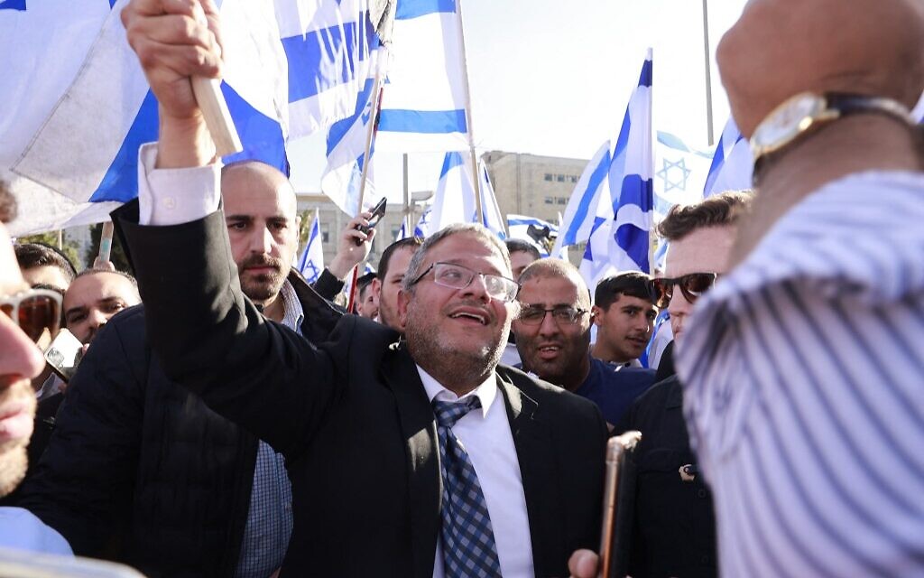 Le député Itamar Ben Gvir, chef de la faction d'extrême-droite Otzma Yehudit, hissant un drapeau israélien sur la place Safra, à Jérusalem, le 20 avril 2022. (Crédit : Menahem Kahana/AFP)