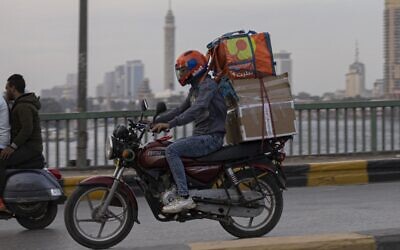 Un livreur roule sur sa moto dans la capitale égyptienne, Le Caire, le 21 avril 2022, pendant le mois sacré musulman du Ramadan. (Crédit : Khaled DESOUKI / AFP)